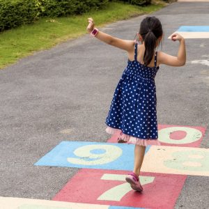 A child in a dress playing hopscotch